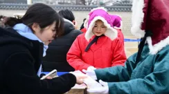 Warga Seoul menerima lukisan tradisional sehwa di Istana Gyeongbok sebagai bagian dari perayaan Tahun Baru Imlek pada 30 Januari 2025.