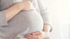 Young pregnant woman holds her hands on her swollen belly. Love
