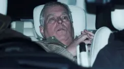 Andrew Mountbatten-Windsor duduk di kursi belakang mobil pada malam hari dengan ekspresi serius saat difoto dari luar kendaraan.